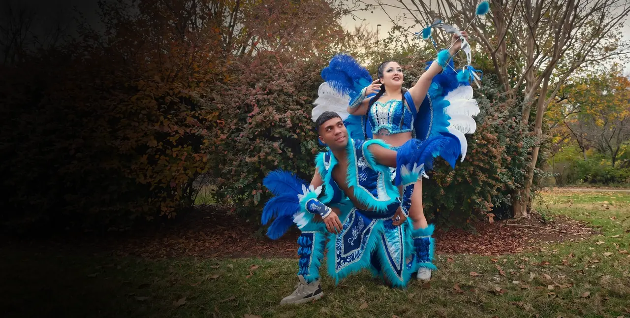Pareja con el traje de Tobas azul: ella levanta el arco, él arrodillado con chaqueta y faldón